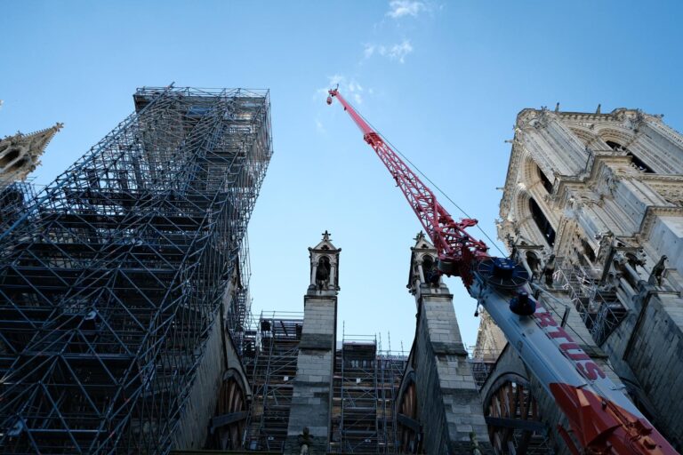 cranes in front of notre dame cathedral in paris
